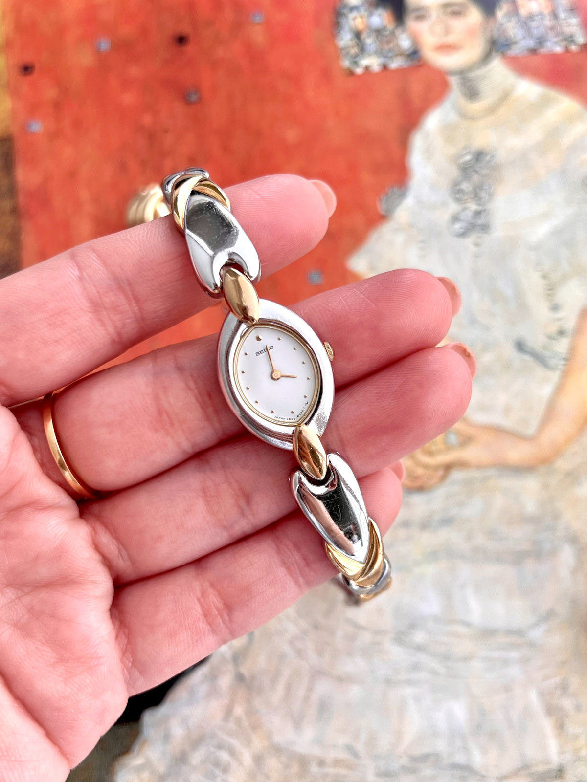 Handheld close view of the Seiko white dial, applied gold dot markers, two gold tone hands and dial signature