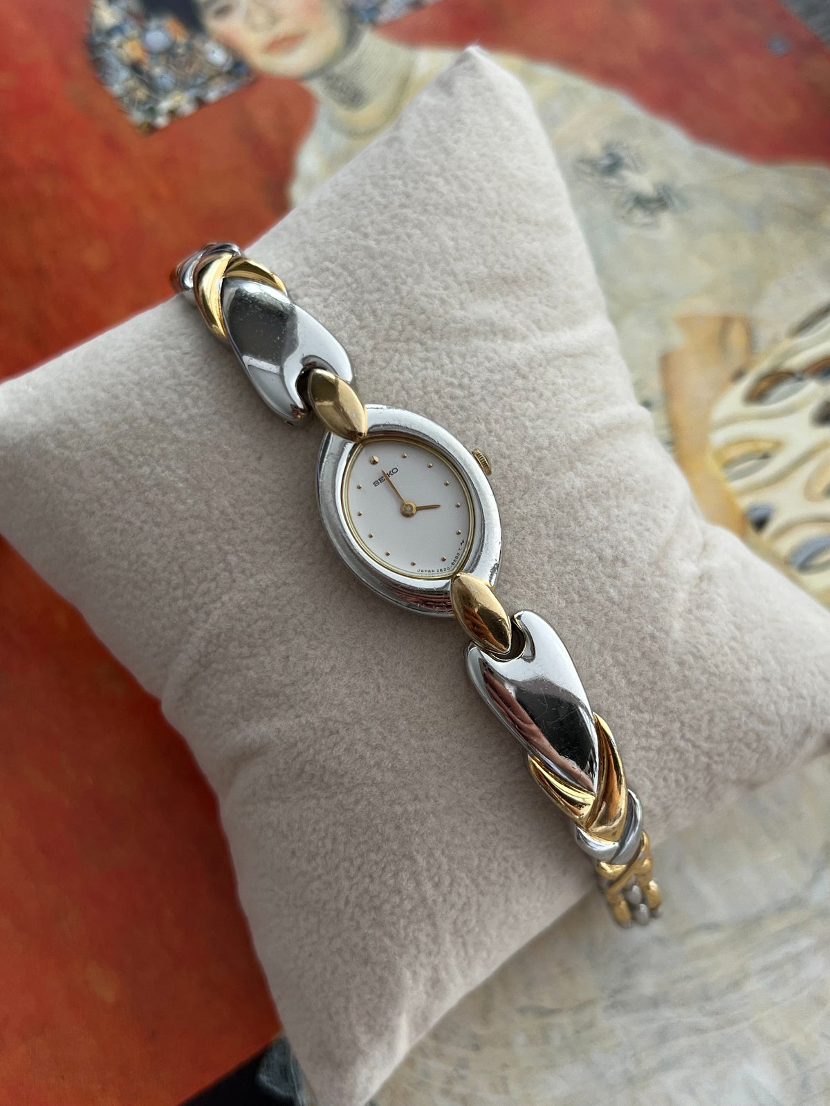 Close view of the Seiko white oval dial, gold tone hands and curved two tone bracelet links