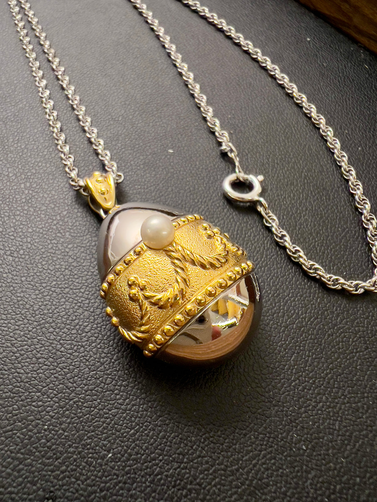 Tasaki egg pendant watch with a gold-tone case, white dial, and pearl detail.