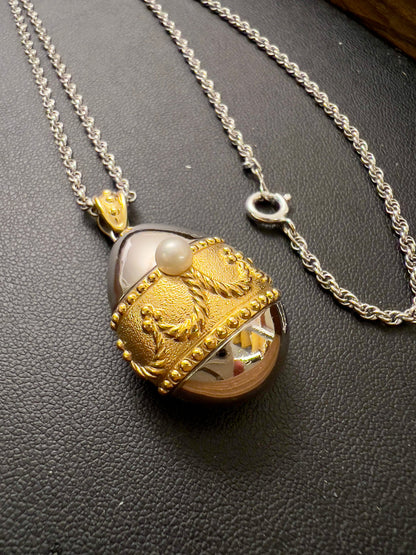 Tasaki egg pendant watch with a gold-tone case, white dial, and pearl detail.