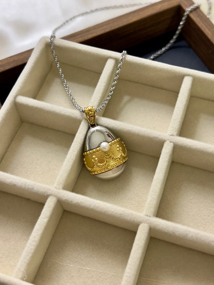 Tasaki egg pendant watch with a gold-tone case, white dial, and pearl detail.