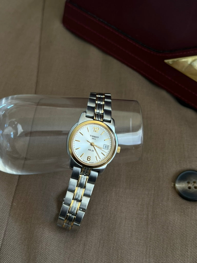 Front view of the Tissot PR 50 with applied gold tone numerals at twelve and six and full two tone bracelet