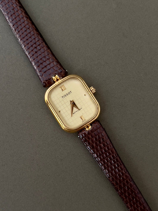 Front view of the Tissot Stylist gold oval women's watch with champagne patterned dial.