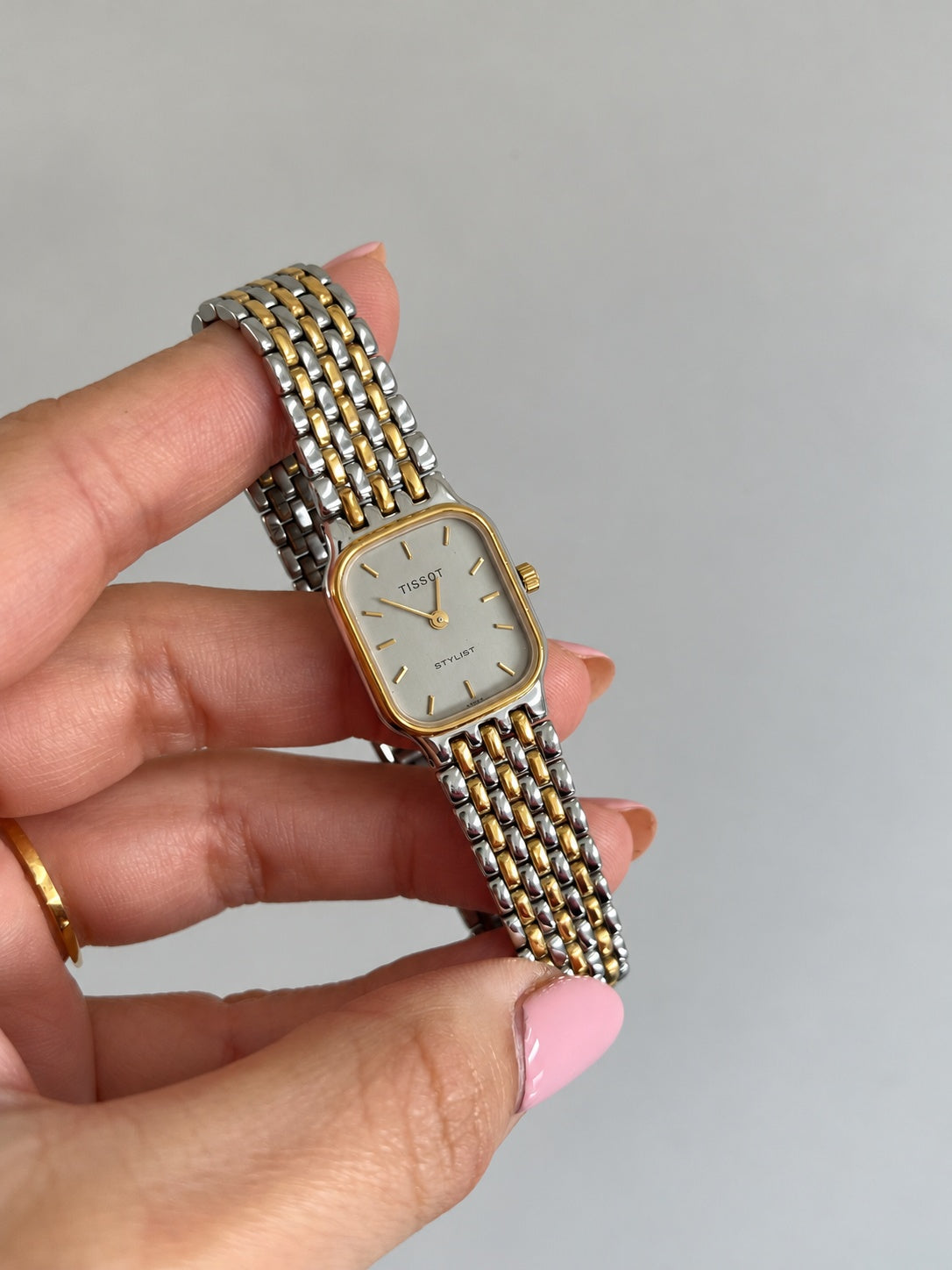 Angled view of the Tissot Stylist gold tone bezel and three gold tone rows running through the silver bracelet.