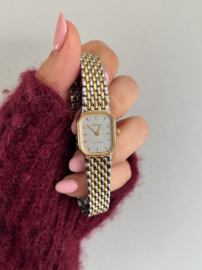 Front view of the Tissot Stylist with pale silver grey dial, gold tone baton markers and two tone link bracelet.