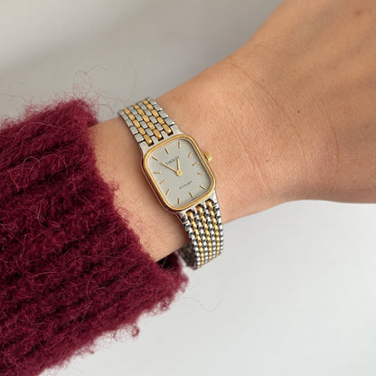 Tissot Stylist silver grey dial two tone women’s watch worn beside a burgundy knit sleeve.
