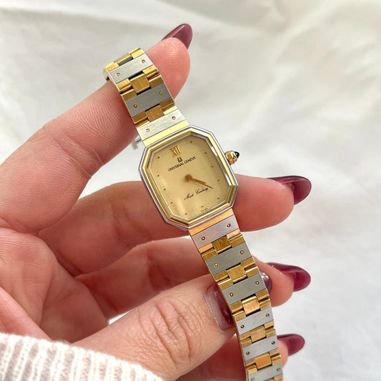 Universal Genève Mark Century women’s two tone Swiss watch with faceted octagonal case, champagne dial and integrated bracelet on wrist.