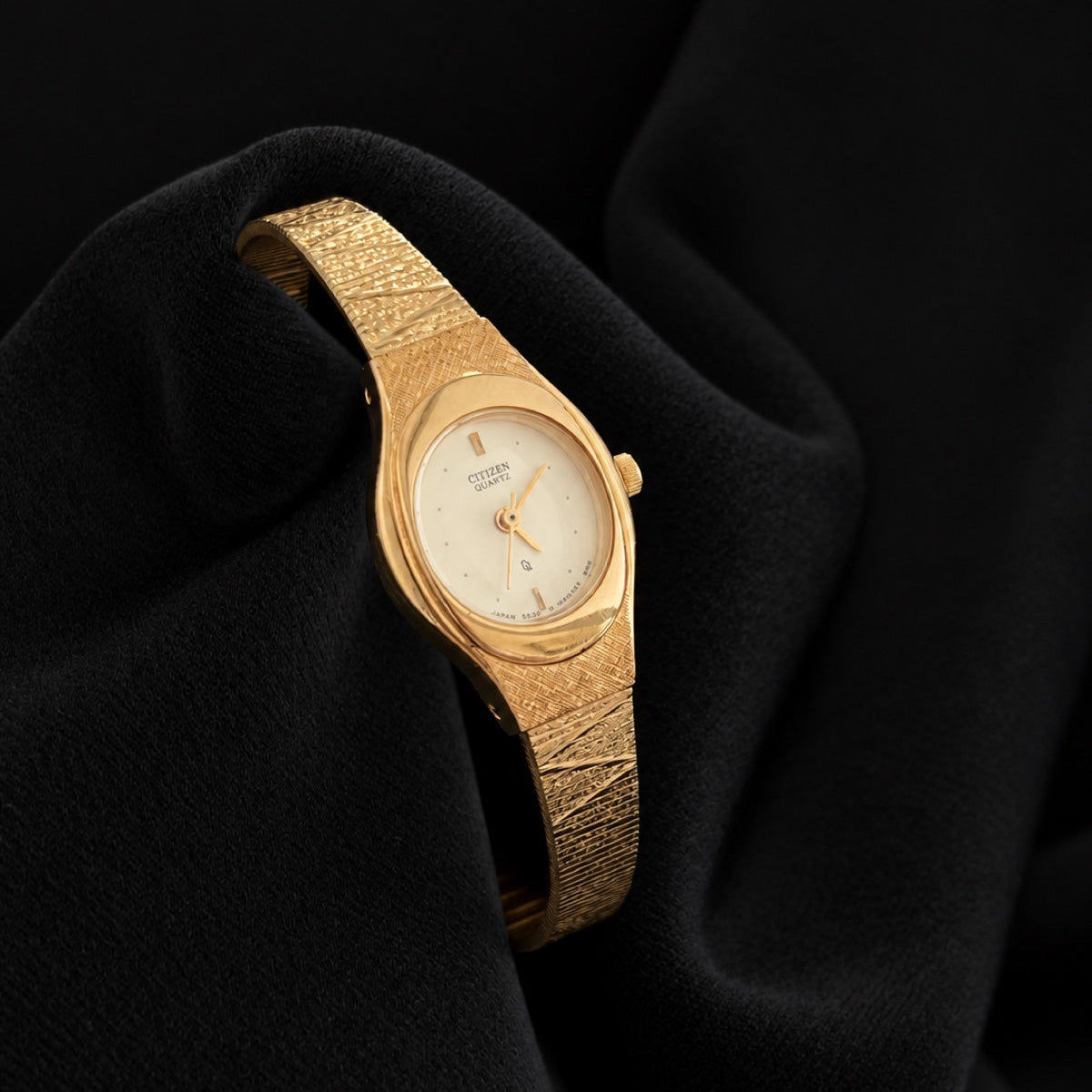 Three-quarter view of Citizen CQ 5930-S25350 with oval champagne dial and textured integrated gold-tone bracelet.