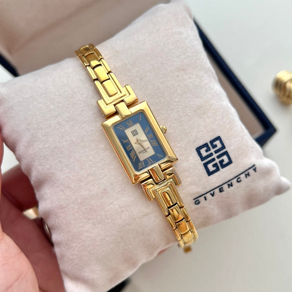 Vintage Givenchy women’s gold-tone bangle watch with a rectangular blue Roman numeral dial and geometric bracelet displayed in a Givenchy presentation box