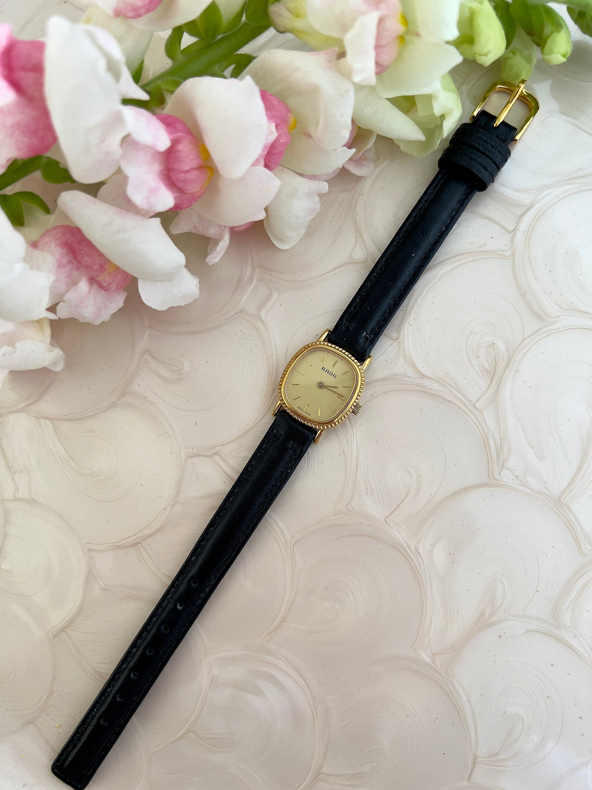 Rado Gold Cushion Women’s Watch with Fluted Case — full cushion watch and black strap.