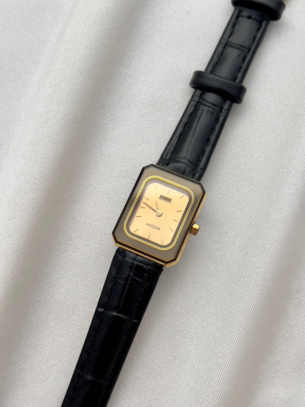 Vintage Rado DiaStar tank women's watch with a champagne dial and black leather strap, shown in an alternate front view.