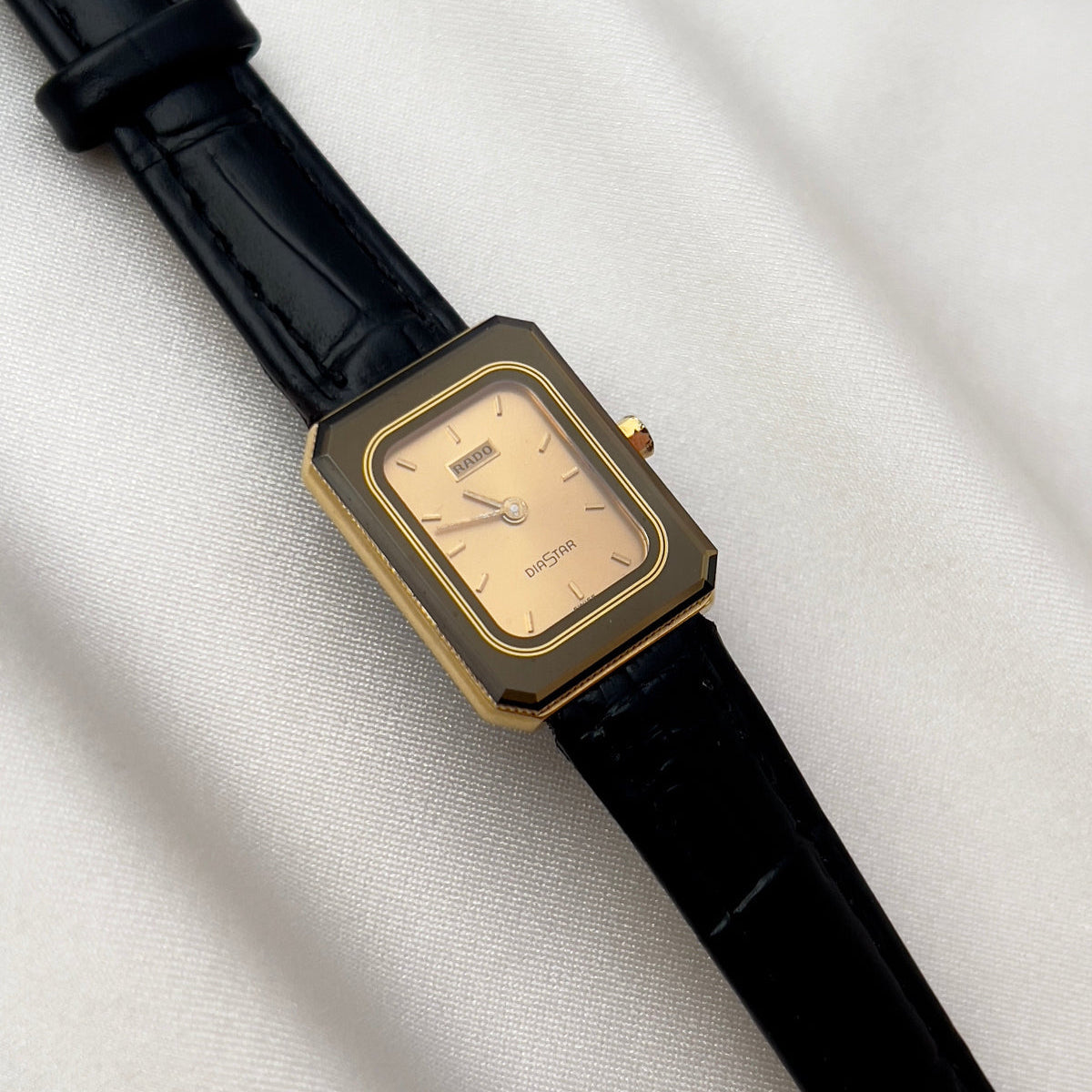 Vintage Rado DiaStar tank women's watch with a champagne dial and black leather strap, shown in a close front view.