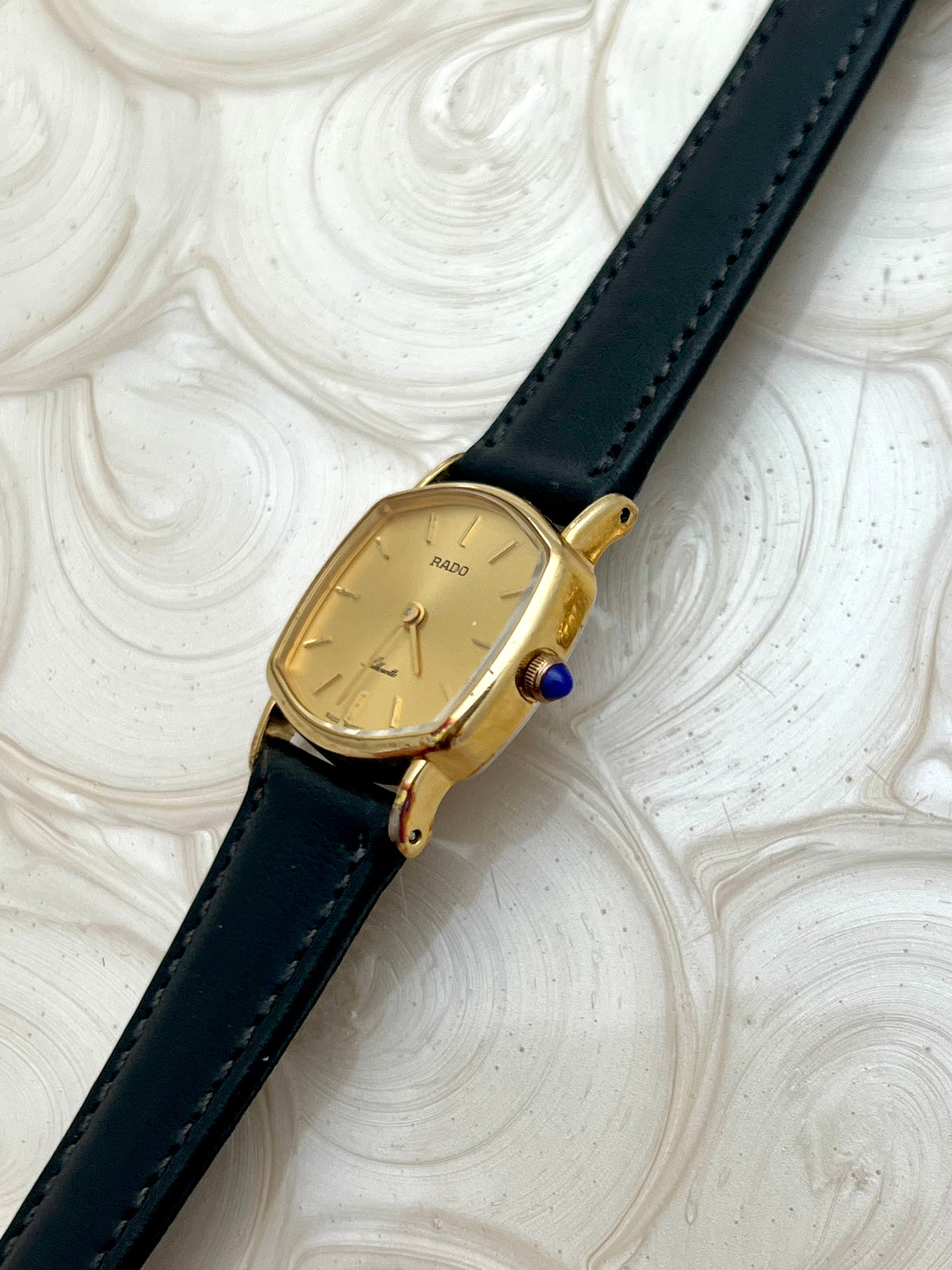 Vintage Rado Soft Octo Silhouette women's watch with a gold-tone case and black leather strap, shown in profile to reveal the sculpted case.