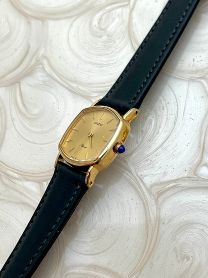 Vintage Rado Soft Octo Silhouette women's watch with a gold-tone case and black leather strap, shown in profile to reveal the sculpted case.