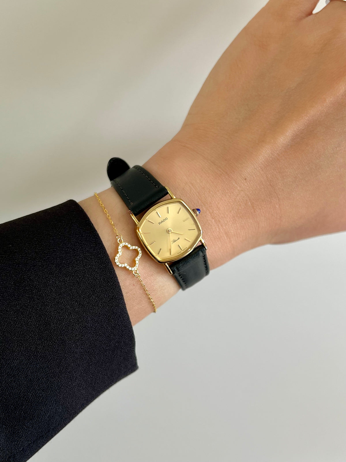 Vintage Rado Soft Octo Silhouette women's watch with a gold-tone case and black leather strap, worn on the wrist.