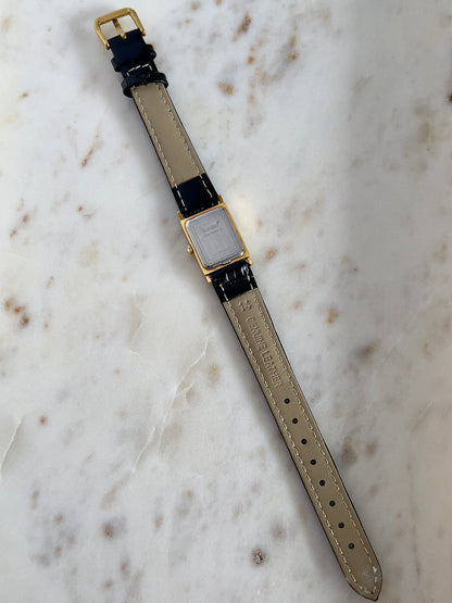 Vintage Rado tank women's watch with a gold dial, diamond accents and black leather strap, shown from the back with the full strap.