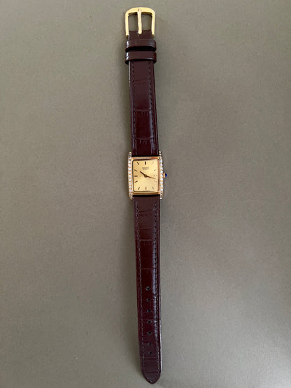 Vintage Rado tank women's watch with a champagne dial, diamond-set case and burgundy leather strap, shown full length.