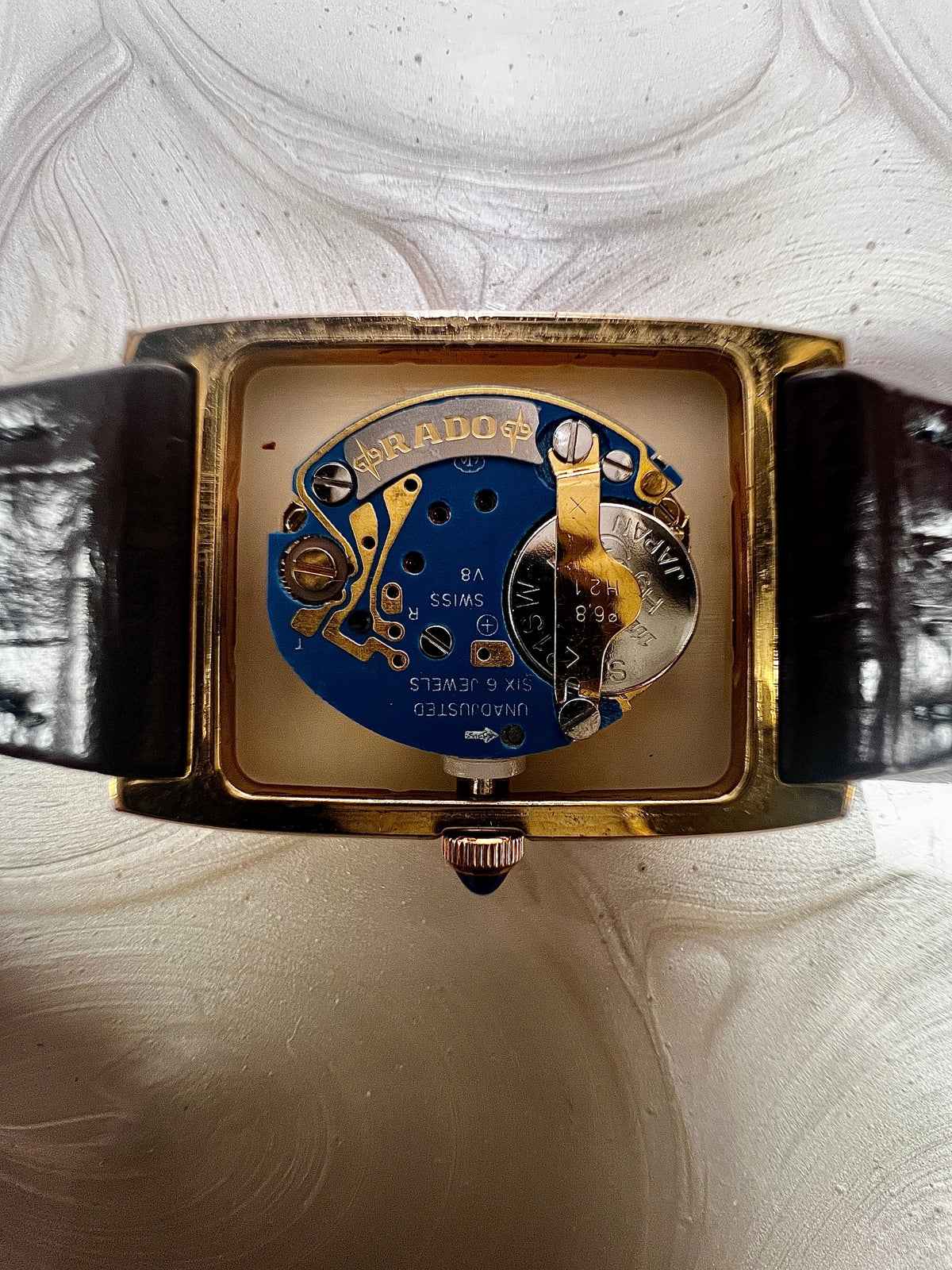 Vintage Rado tank women's watch with a champagne dial, diamond-set case and burgundy leather strap, shown with the case open to reveal the quartz movement.