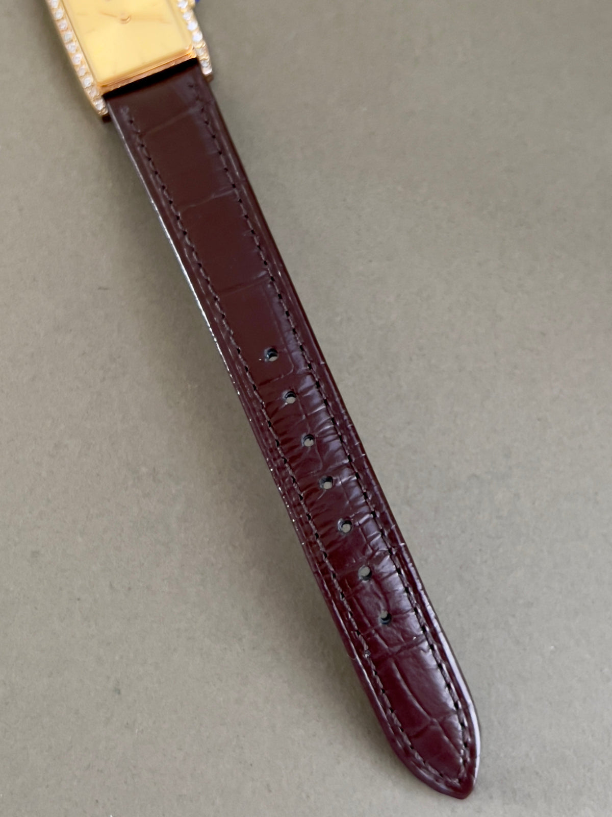 Vintage Rado tank women's watch with a champagne dial, diamond-set case and burgundy leather strap, shown with the burgundy leather strap tip.