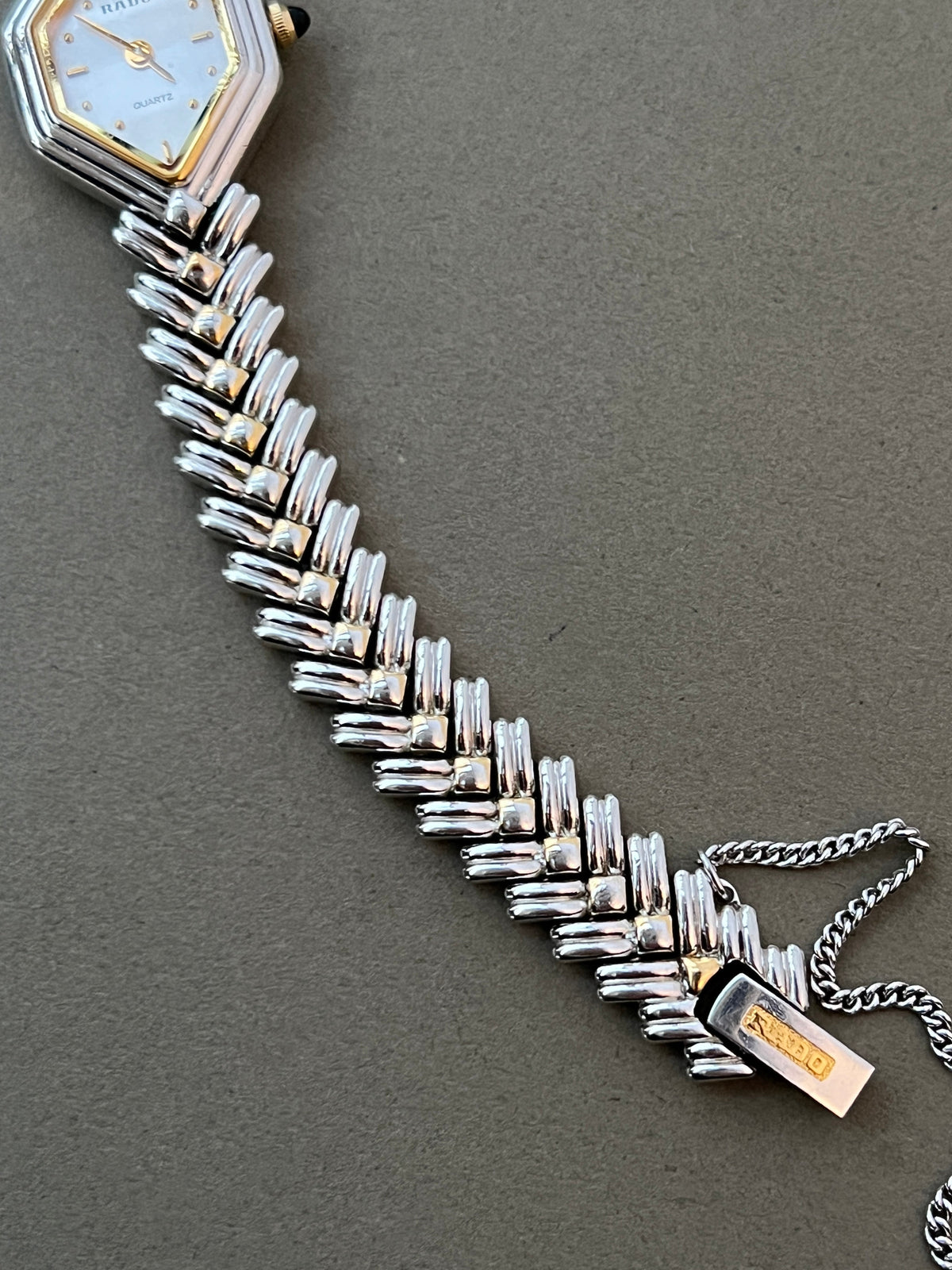 Vintage Rado two-tone sculpted women's watch with a pearl dial and herringbone bracelet, shown in a close detail view.