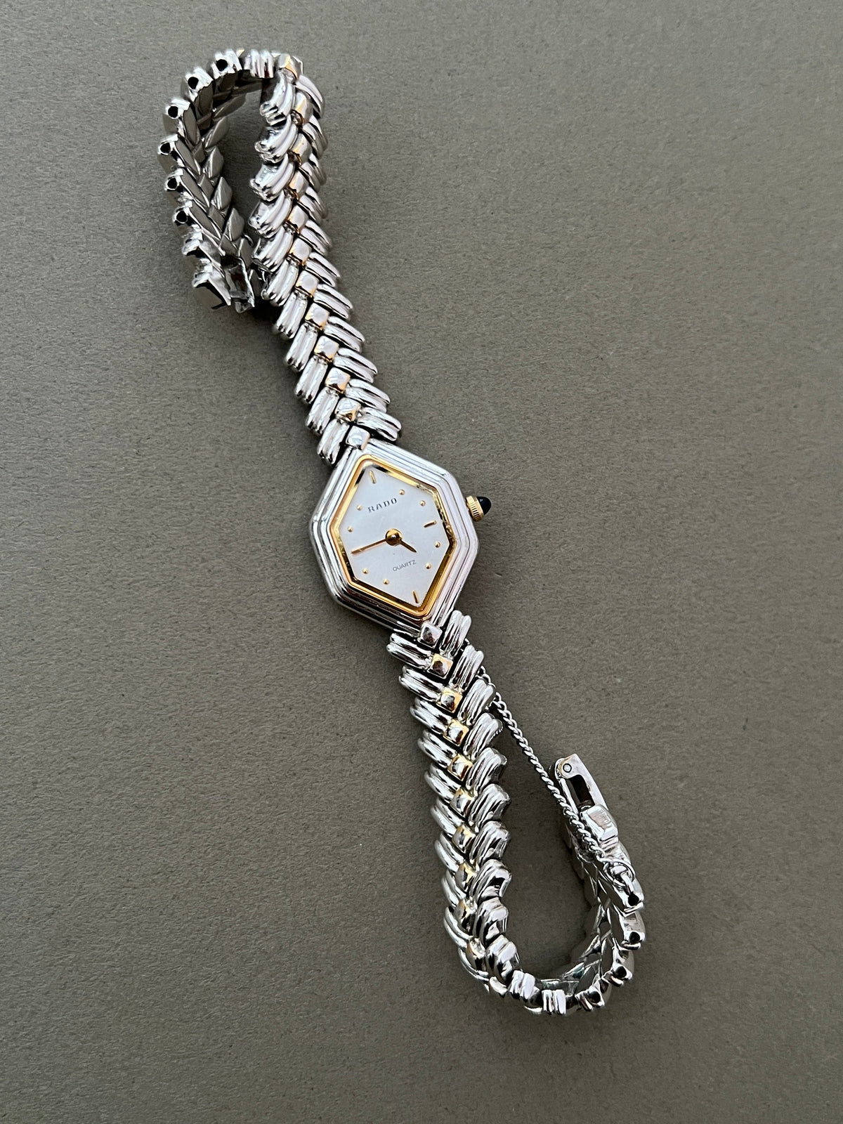 Vintage Rado two-tone sculpted women's watch with a pearl dial and herringbone bracelet, shown with the sculpted bracelet curved.