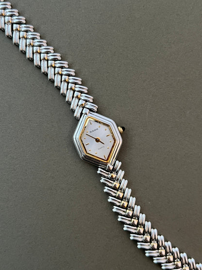 Vintage Rado two-tone sculpted women's watch with a pearl dial and herringbone bracelet, shown front-facing with the bracelet extended.