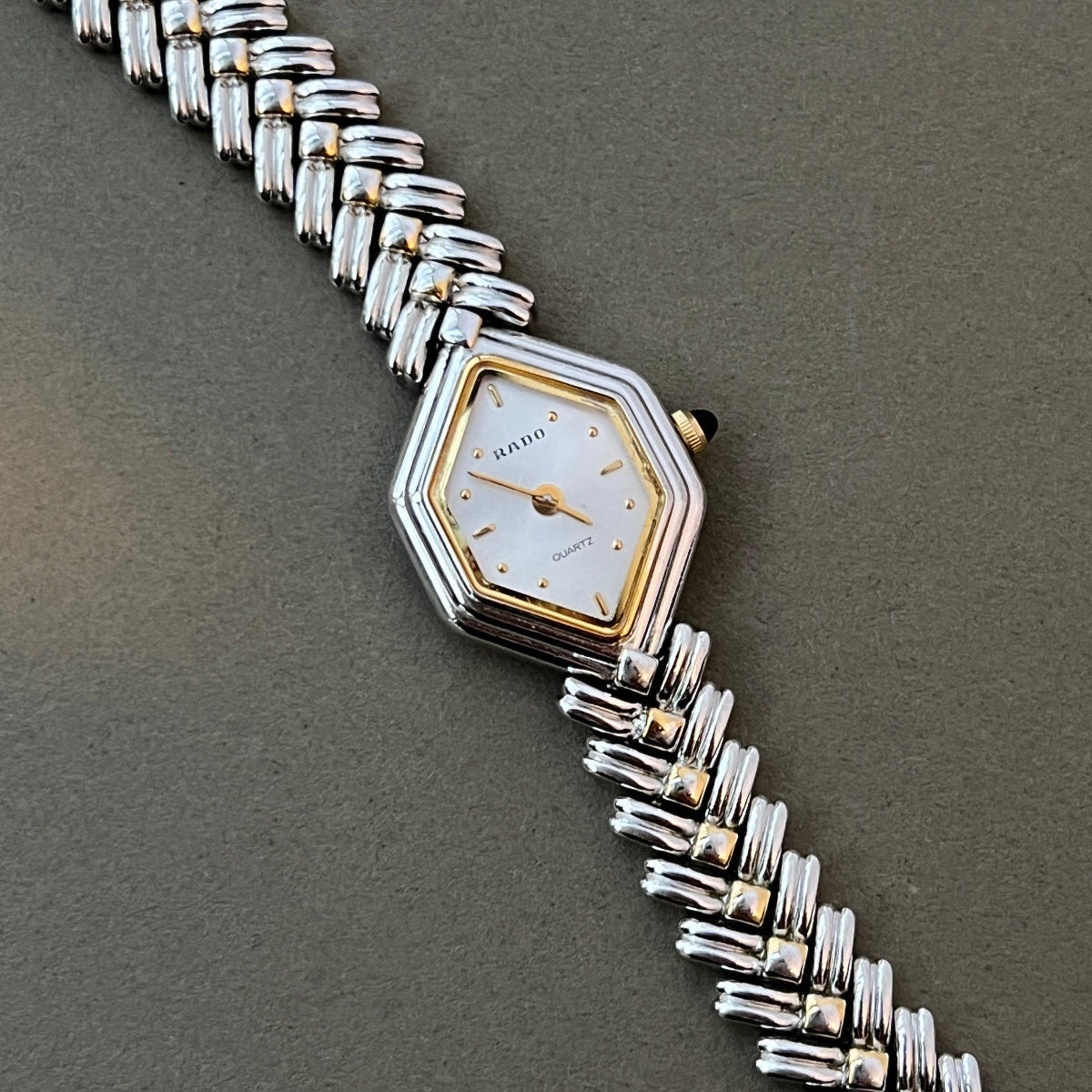Vintage Rado two-tone sculpted women's watch with a pearl dial and herringbone bracelet, shown in a close front view.