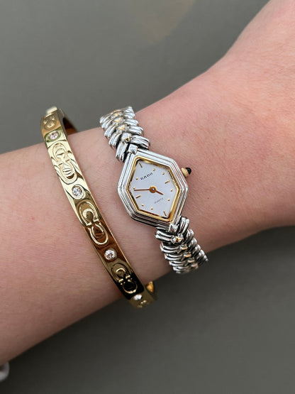 Vintage Rado two-tone sculpted women's watch with a pearl dial and herringbone bracelet, worn on the wrist.