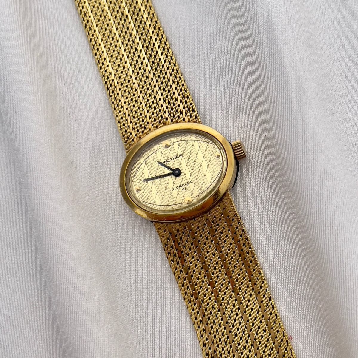Waltham vintage gold ladies watch with textured champagne dial and integrated mesh bracelet.