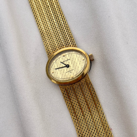 Waltham vintage gold ladies watch with textured champagne dial and integrated mesh bracelet.