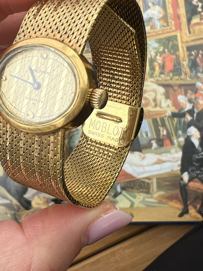 Waltham hand-wound ladies watch with gold-tone oval case and woven mesh bracelet.