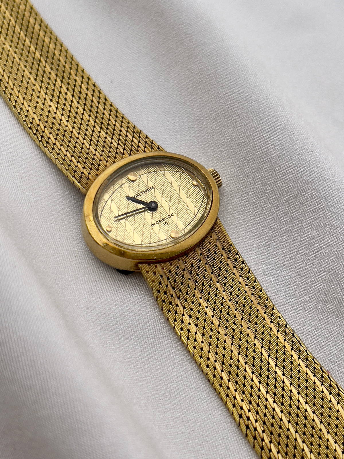 Vintage Waltham watch with champagne dial, blackened hands and fine gold mesh bracelet.