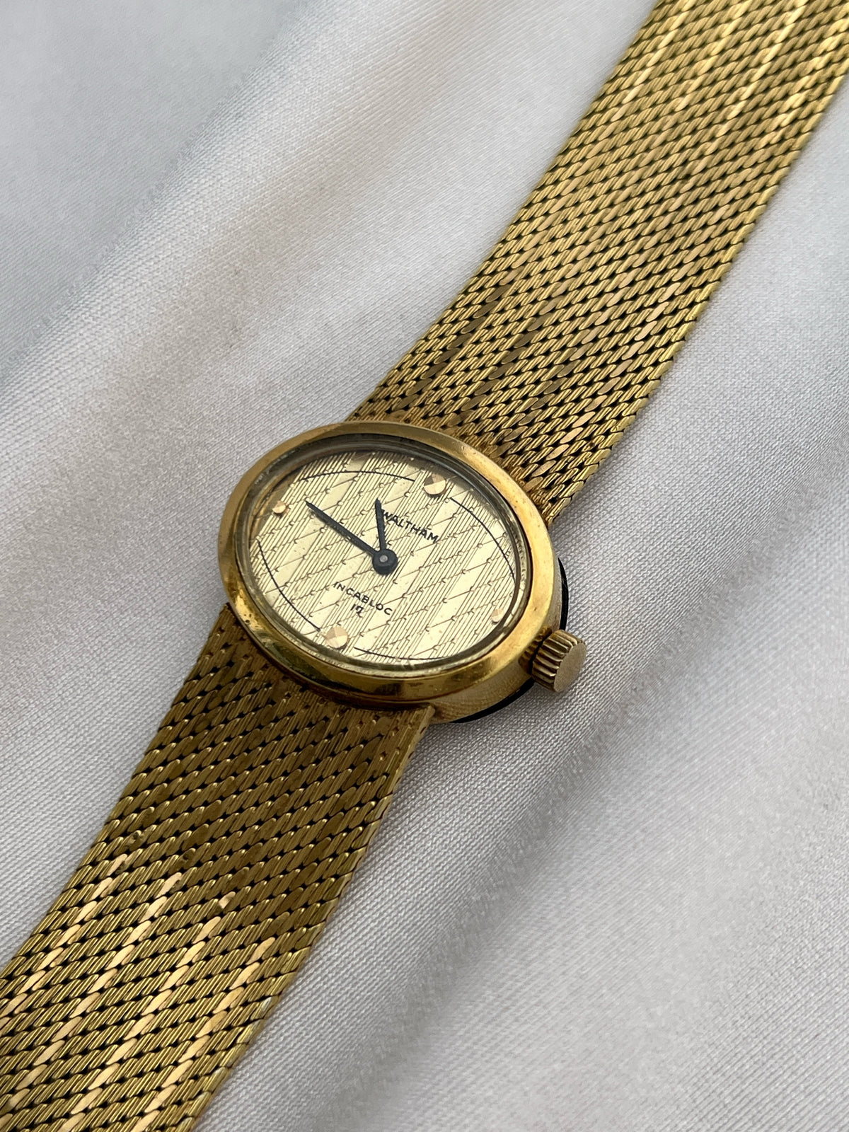 Front view of the Waltham gold-tone watch with textured dial and mesh bracelet.