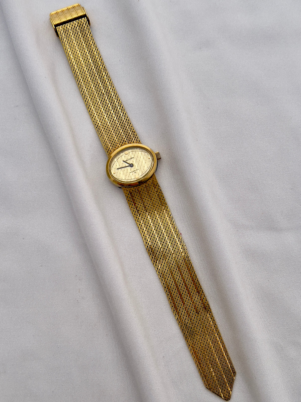 Gold-tone Waltham oval watch case with integrated Moblot mesh bracelet.