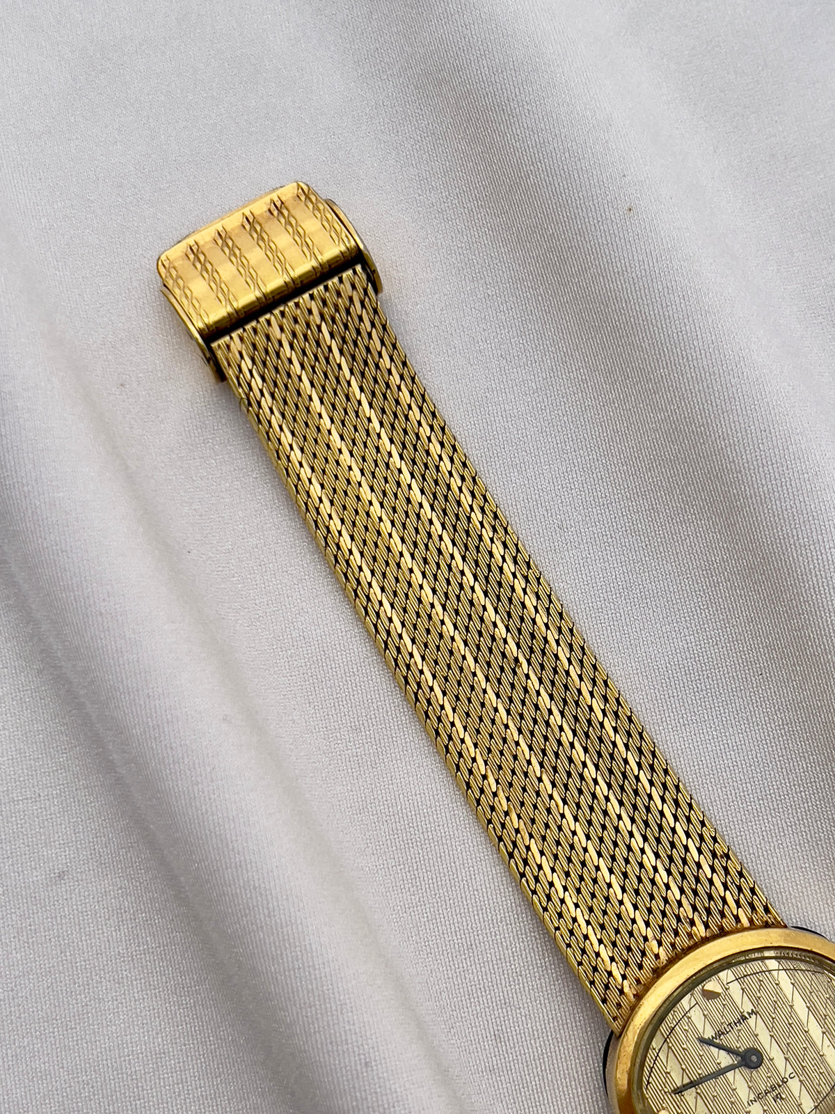Vintage Waltham mechanical ladies watch with gold-tone case and woven bracelet.