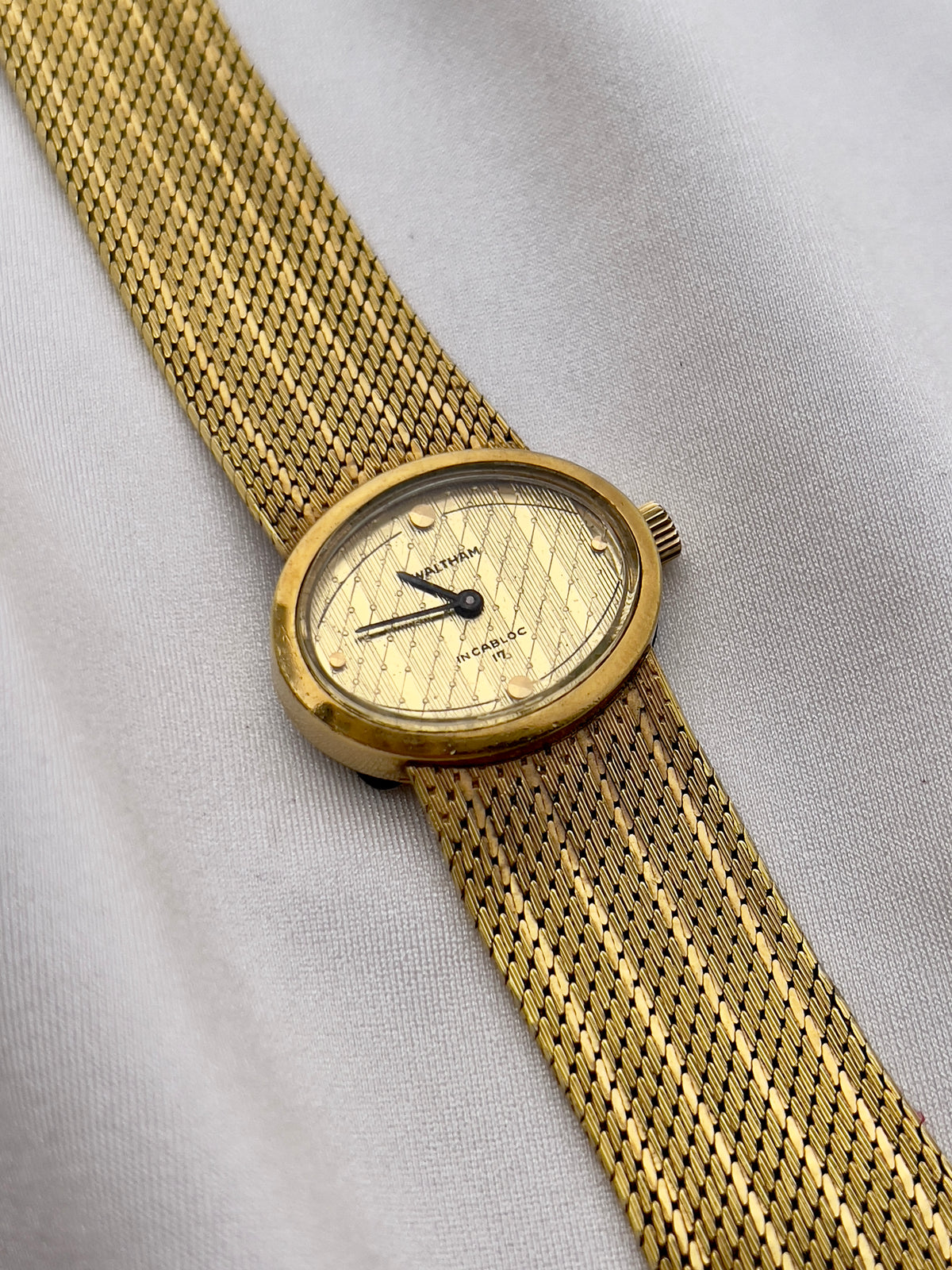 Gold-tone Waltham watch with integrated mesh bracelet and delicate dial markers.