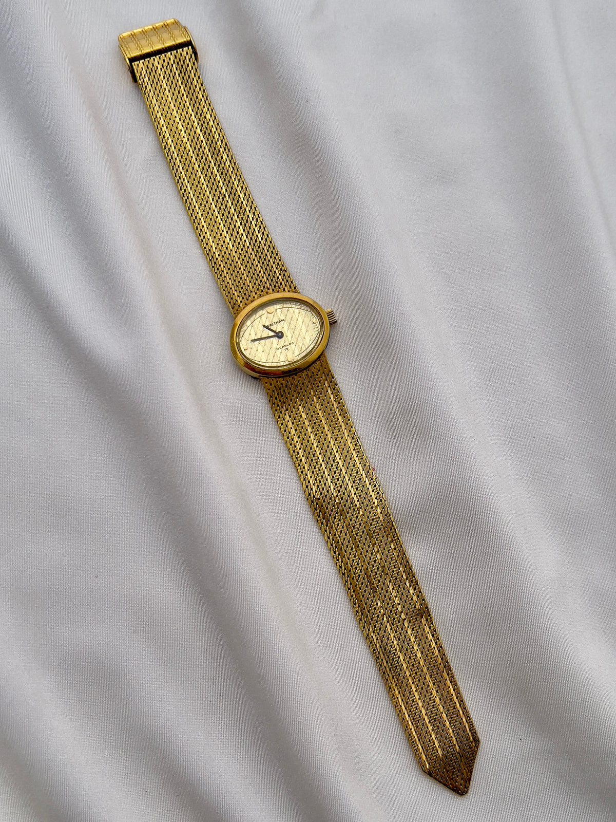 Vintage Waltham ladies timepiece with champagne patterned dial and gold mesh bracelet.