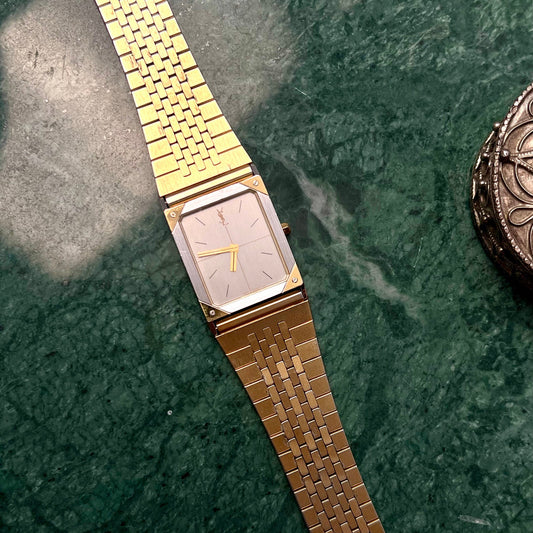 YSL silver and gold rectangular ladies watch with satin dial shown on green marble.