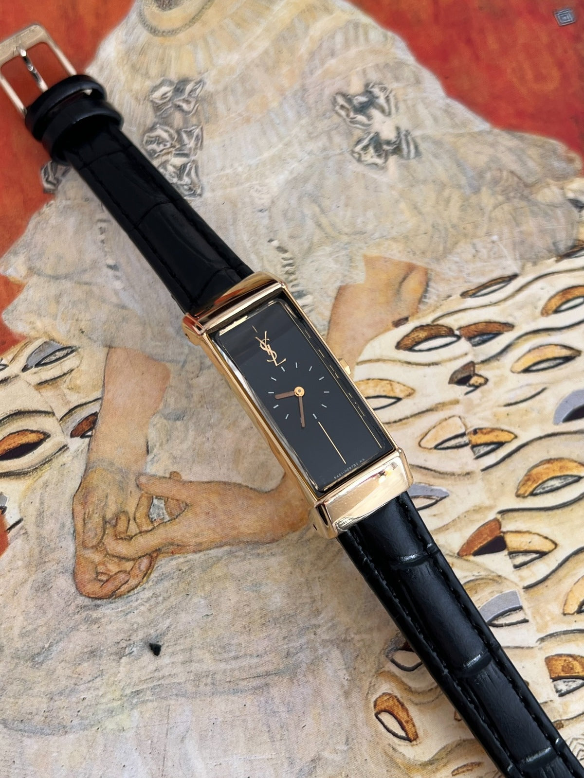 Angled view of the Yves Saint Laurent gold tone tank case, curved end pieces and small crown.