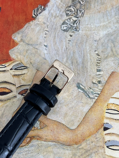 Close view of the pin buckle engraved Yves Saint Laurent on the black embossed leather strap.